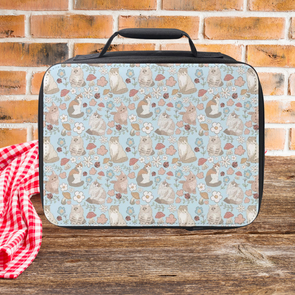 Lunch bag with hand drawn cat & flowers pattern on a wooden picnic table and brick wall background