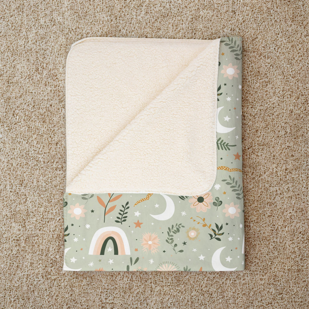 Folded blanket with nature-themed pattern on a beige carpet