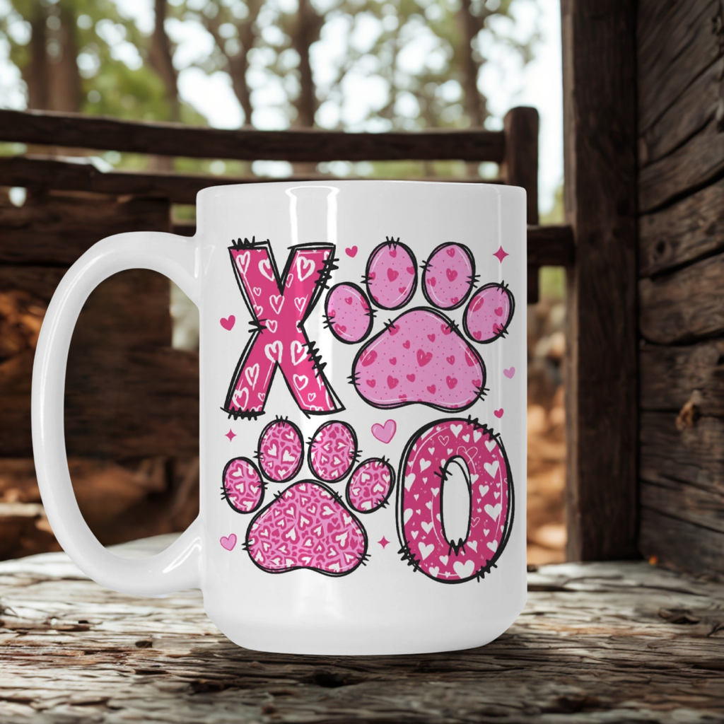 White mug with pink paw prints and hearts on a wooden surface