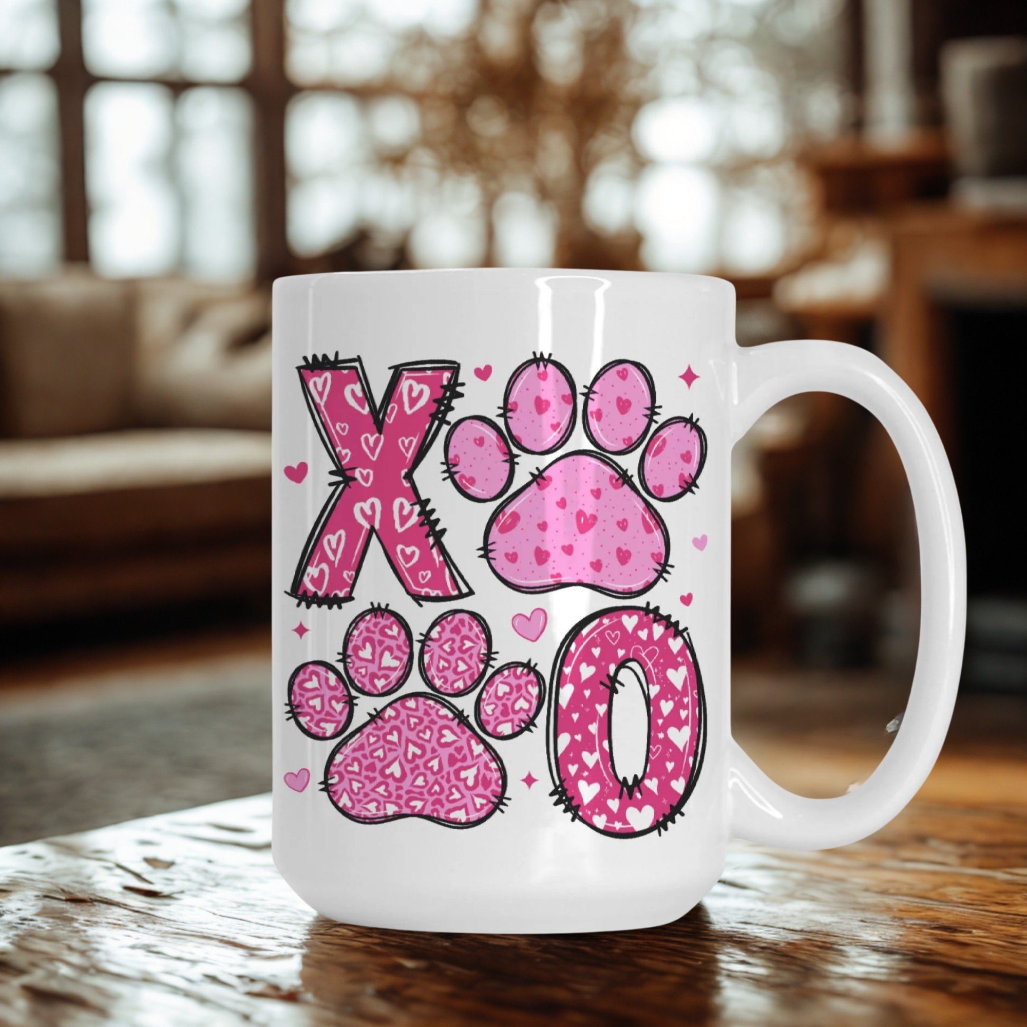 White mug with pink paw prints and hearts design on a wooden surface.