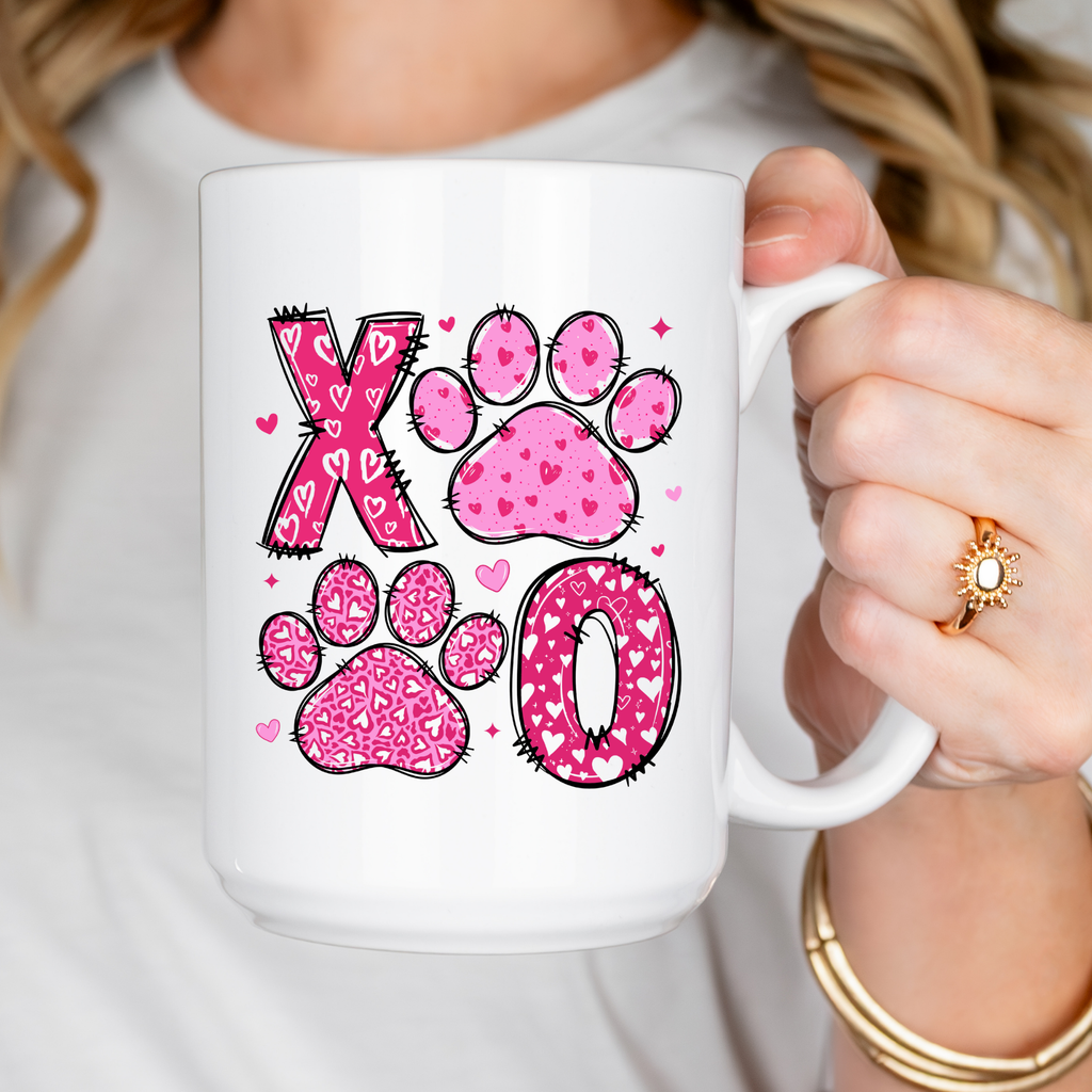 White mug with pink paw print design held by a person