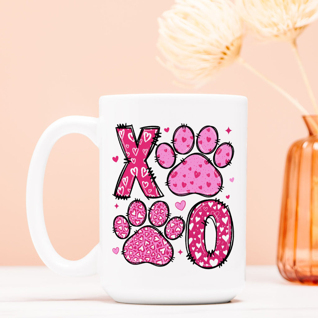 White mug with pink paw prints and heart designs on a light pink background