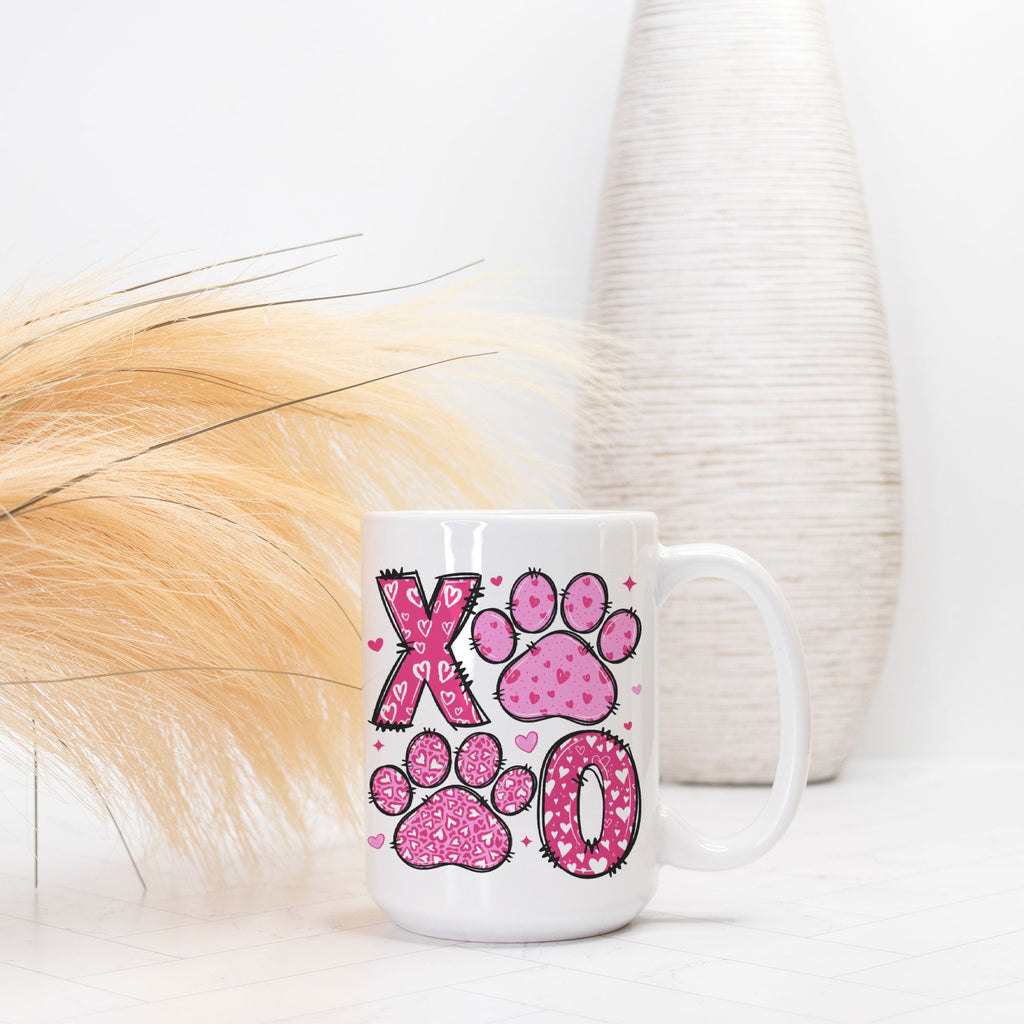White mug with pink paw prints and 'XO' design on a white surface.