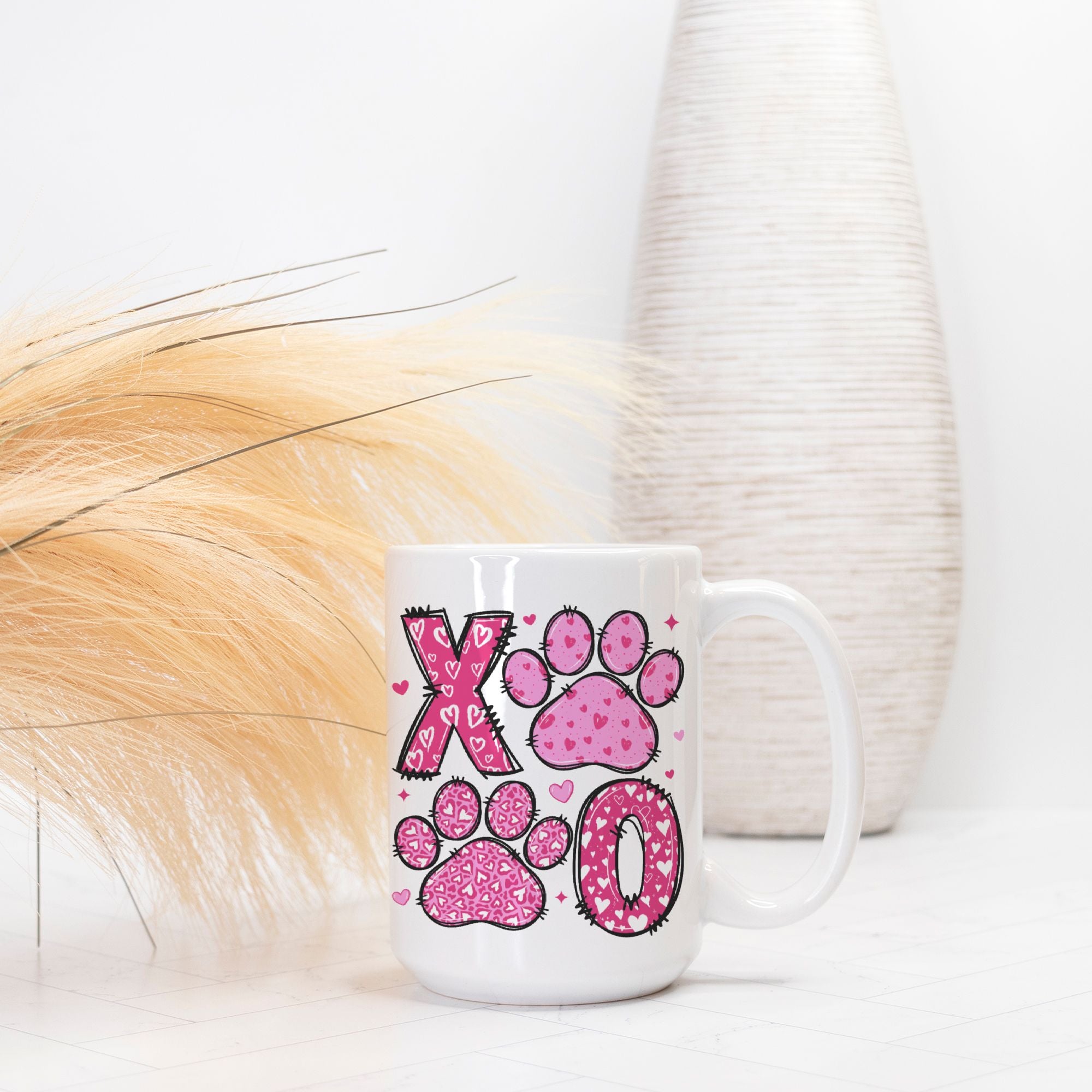 White mug with pink paw prints and 'XO' design on a white surface.