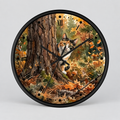 A round wall clock with a black frame and a printed autumn forest scene featuring a calico cat near a tree trunk, shown on a light gray background.