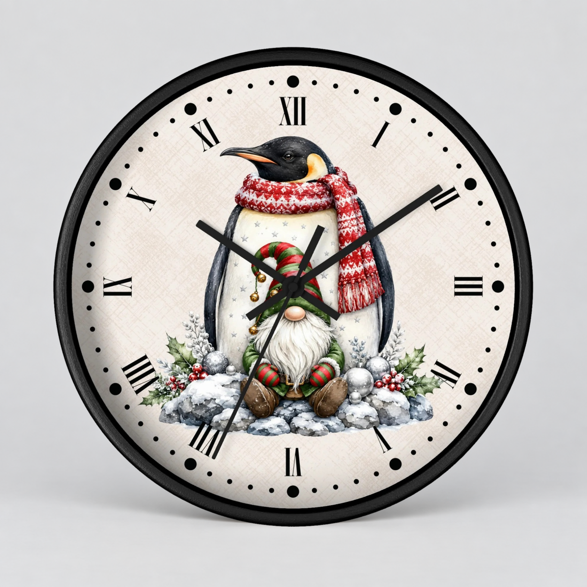 A round wall clock with a black frame and a festive Christmas penguin illustration on the dial. The clock face is off-white with black Roman numerals and black hands, while the penguin wears a red and white knit scarf and sits in a snowy winter scene with greenery.