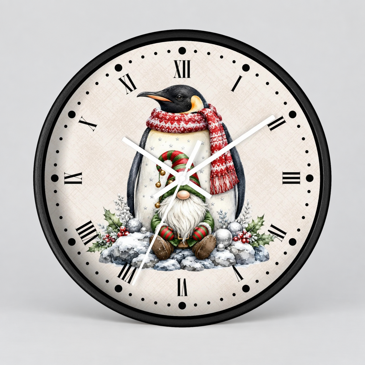 Round wall clock with a black frame and a festive penguin illustration on the dial. The clock face is off-white with black Roman numerals and hands, featuring a penguin in a red knit scarf and a gnome in the snow below, set against a light gray background.