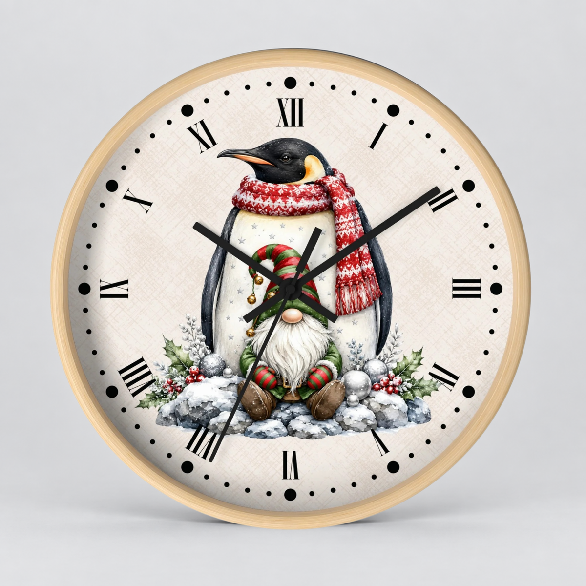 A round wall clock with a light wood frame and a cream-colored face featuring a festive penguin illustration. The penguin is wearing a red and white knit scarf and a red hat, sitting in the snow with a candy cane and greenery accents.