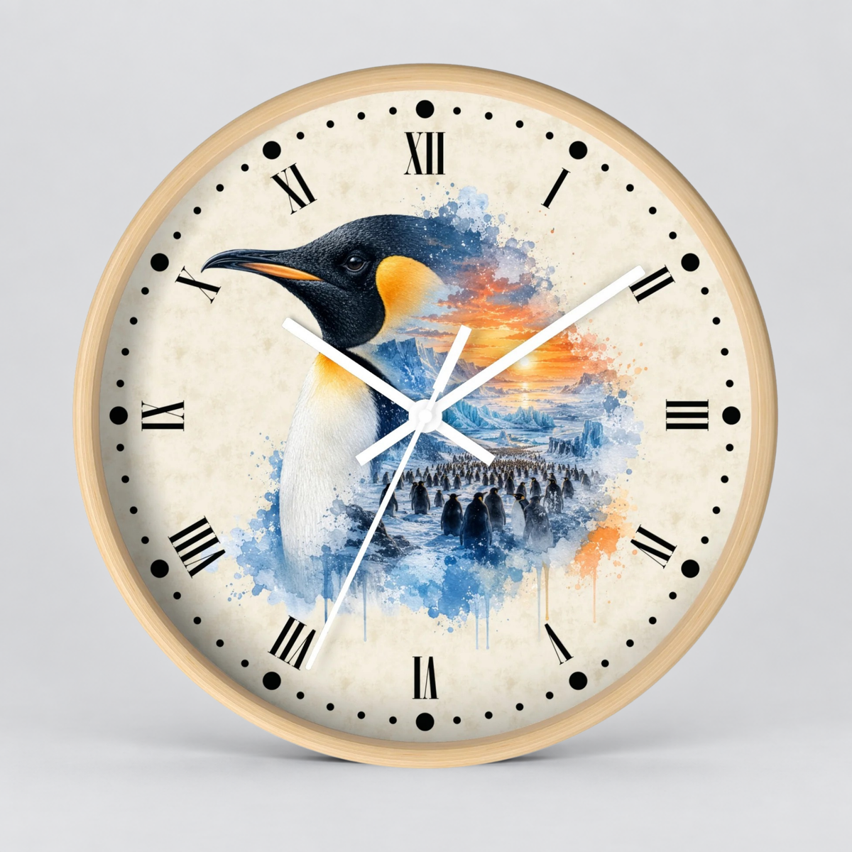 Round wall clock with a light wood frame and a penguin illustration on the face. The clock features black Roman numerals, black dot hour markers, white clock hands, and a watercolor-style penguin design with blue, orange, and white tones on a light cream background.