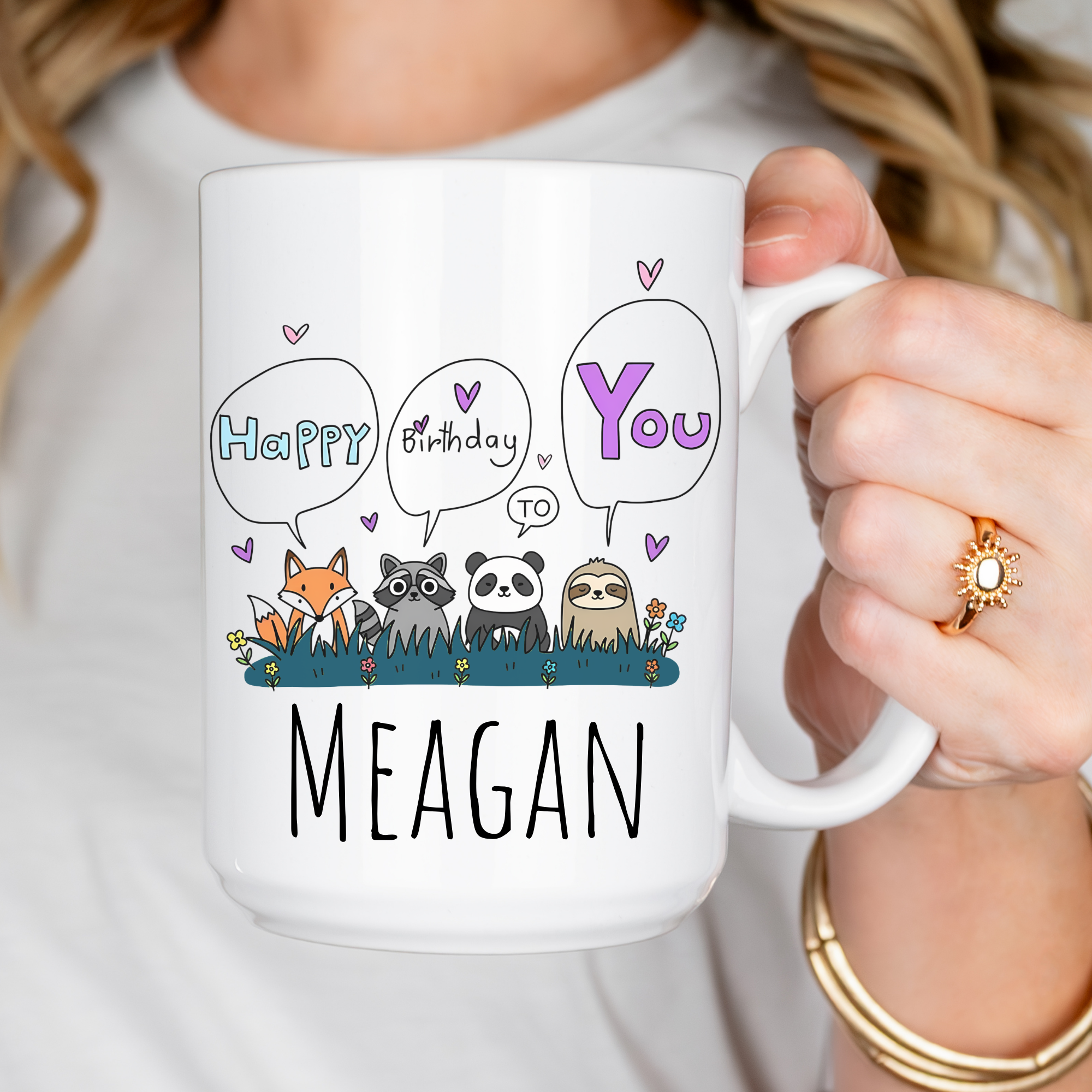 Person holding a white mug with cartoon animals and personalized text