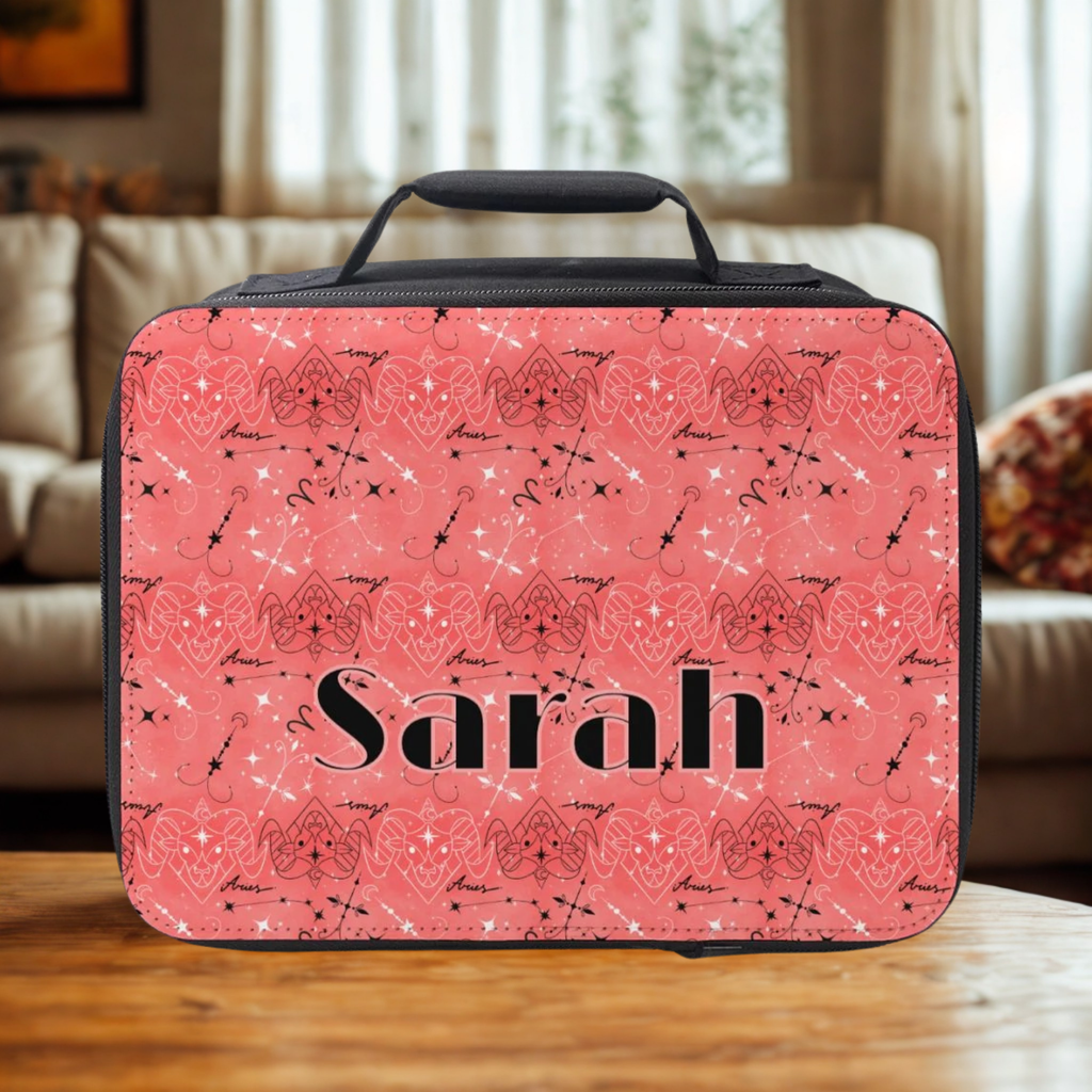 Pink Aries zodiac patterned lunch bag with 'Sarah' printed on it, sitting on a wooden coffee table in a living room.