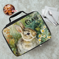 Lunch bag with a rabbit design and 'Clare' text on a table with a drink and utensils.