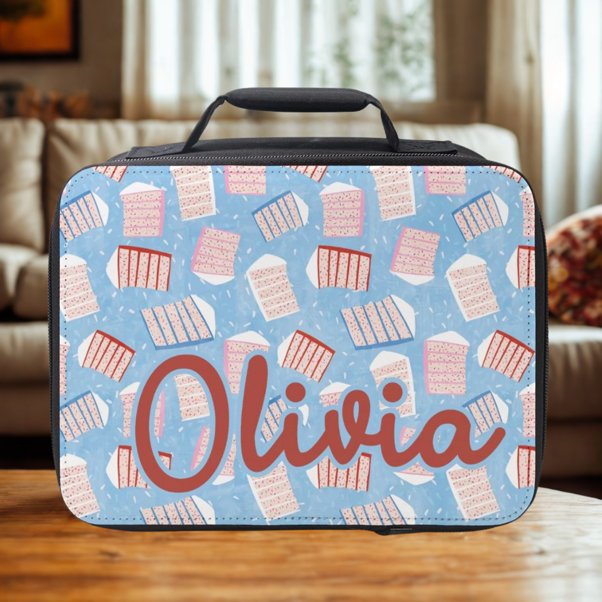  insulated lunch bag with sliced cake pattern and 'Olivia' custom text on a wooden table in a cozy living room.