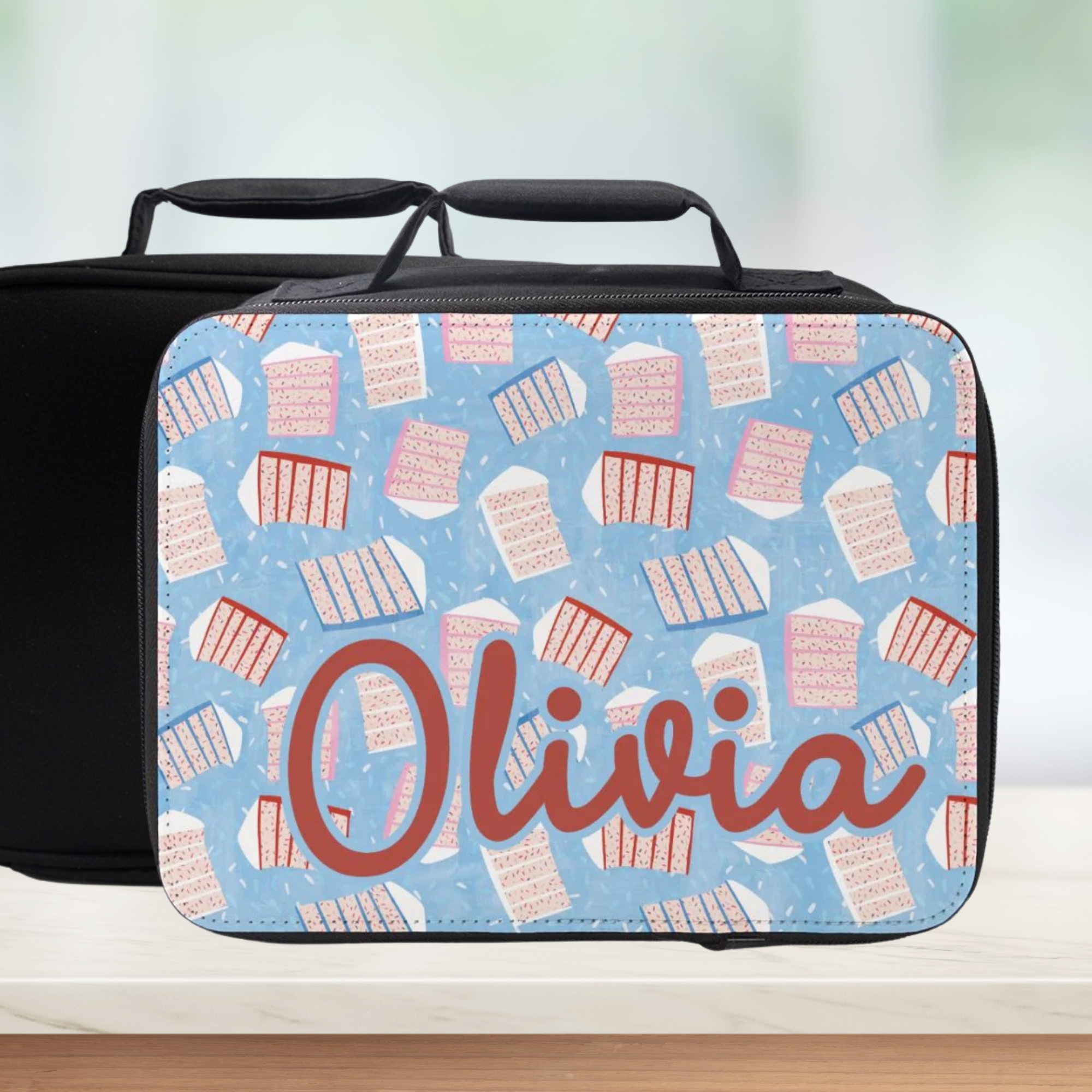 Personalized lunch bag with sliced cake pattern and 'Olivia' custom text on a light blue background.