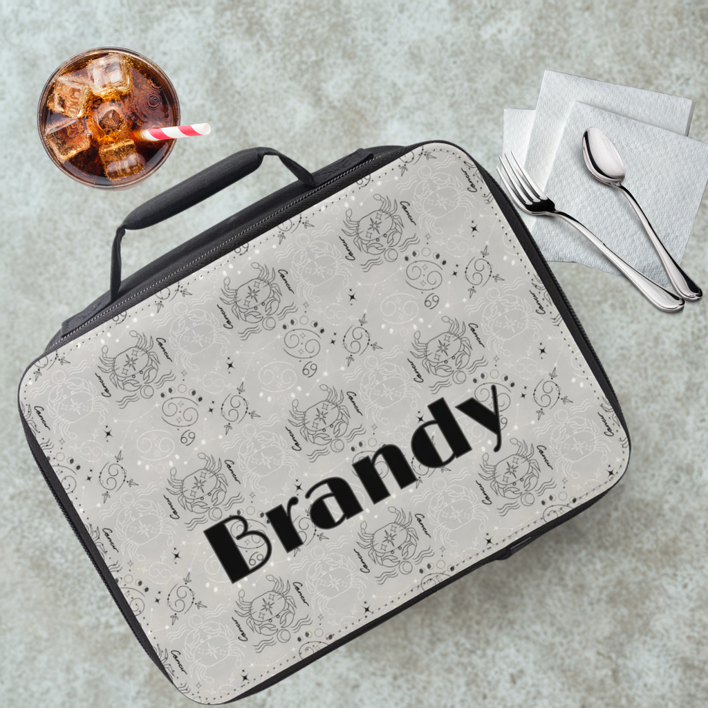 Lunch bag with decorative Cancer zodiac pattern and 'Brandy' custom text on a cafeteria table with a drink and cutlery.