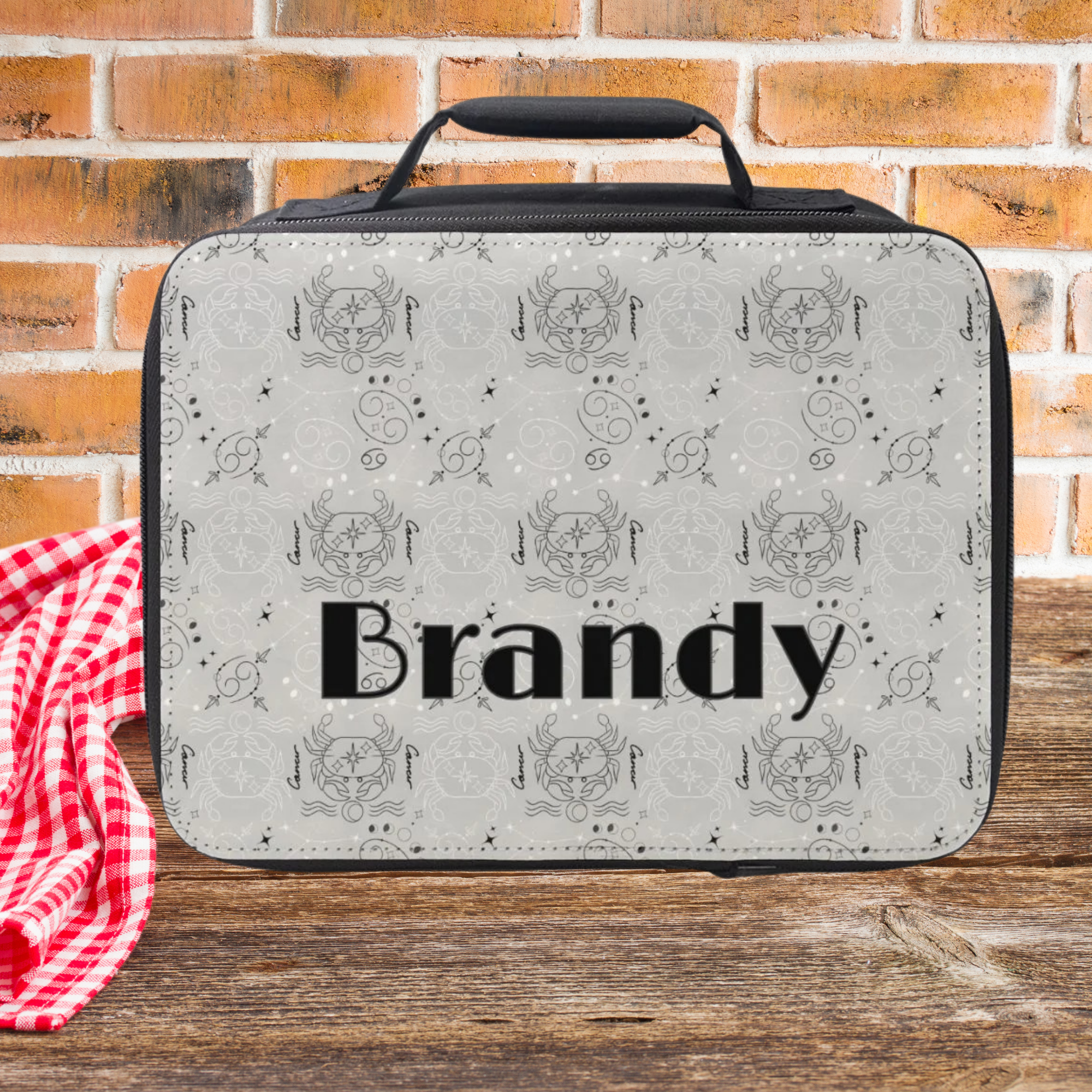 Lunch bag with Cancer zodiac pattern and 'Brandy' printed on it against a brick wall background
