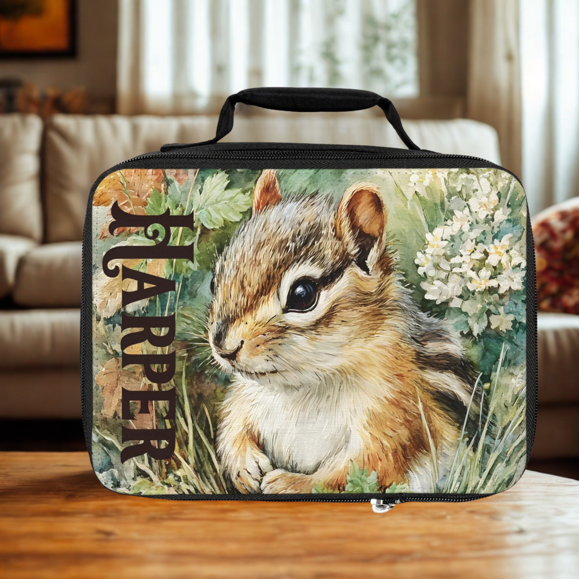  insulated lunch bag with a chipmunk design and 'Harper' custom text on a wooden living room table.