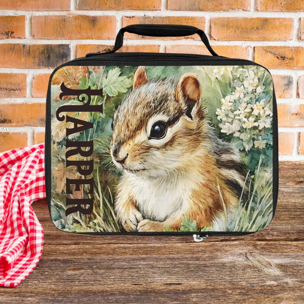 Lunch bag with a chipmunk design and 'Harper' custom text on a wooden picnic table against a brick wall background