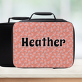 Pink floral patterned suitcase with 'Heather' text on a blurred background
