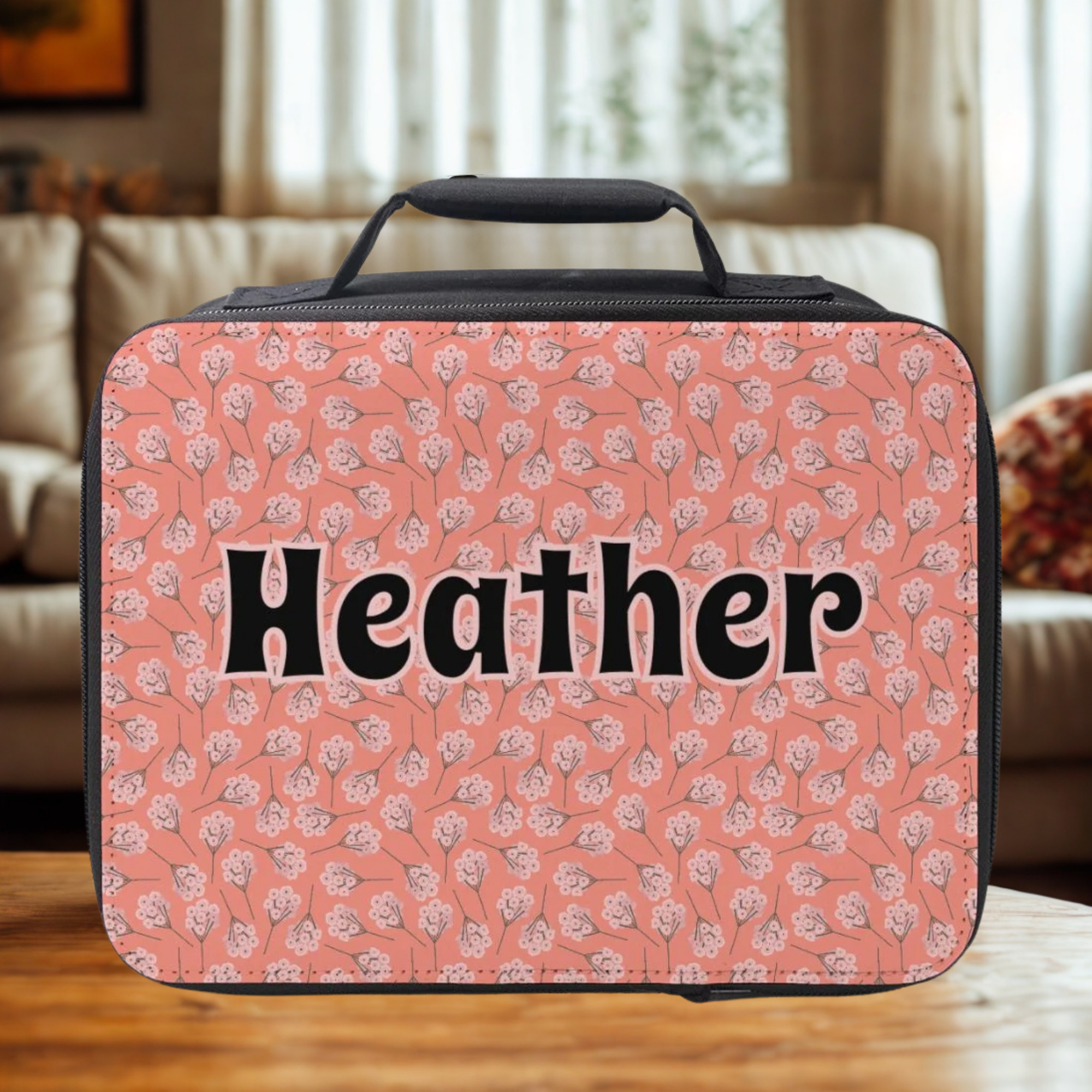 Pink floral patterned lunch bag with 'Heather' text on a wooden surface.