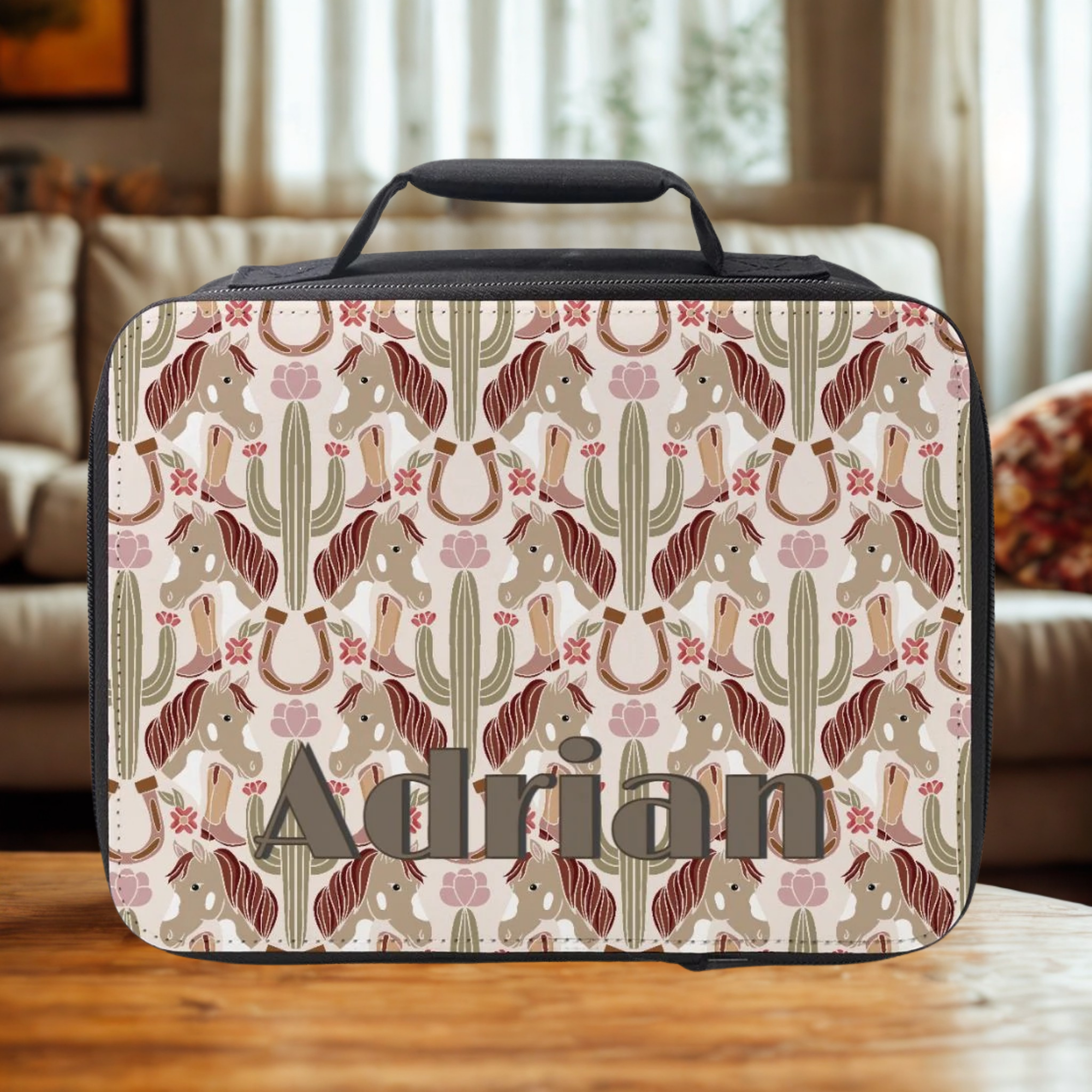  insulated lunch bag with cowgirl pattern and 'Adrian' custom text on a wooden coffee table in a cozy living room.