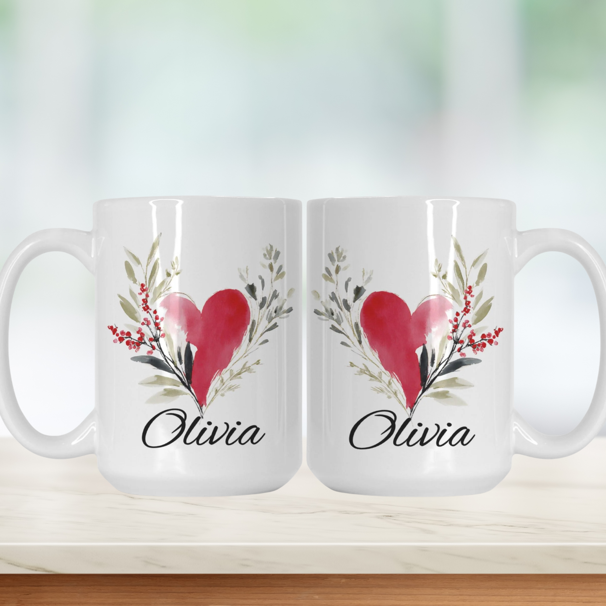Two white mugs with a red heart and green leaves design, featuring the name 'Olivia'.