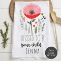 Floral tea towel with 'Blessed to be your child Jenna' text on a wooden surface.