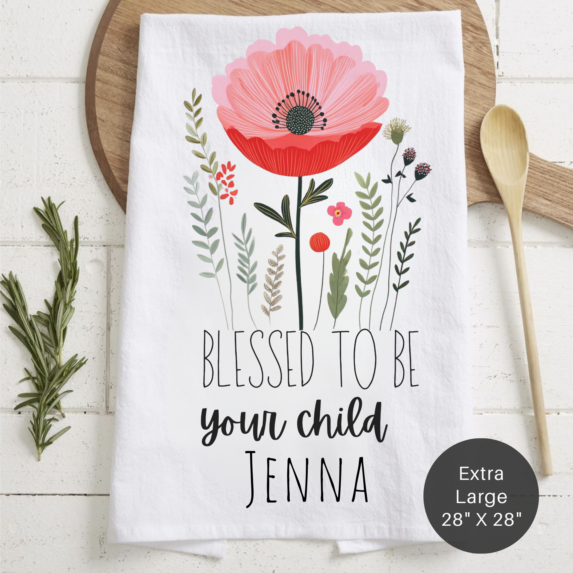 Floral tea towel with 'Blessed to be your child Jenna' text on a wooden surface.