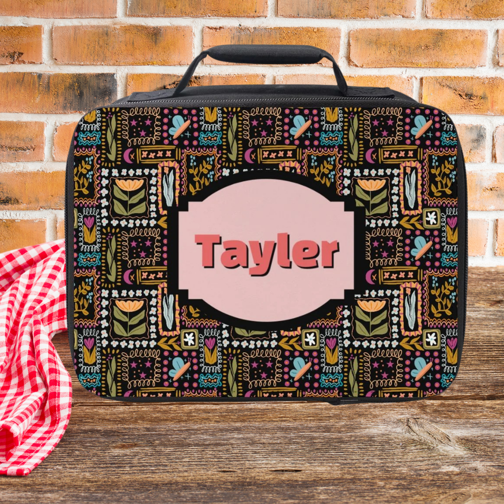 Decorative lunch bag with custom name on a wooden picnic table and brick wall background