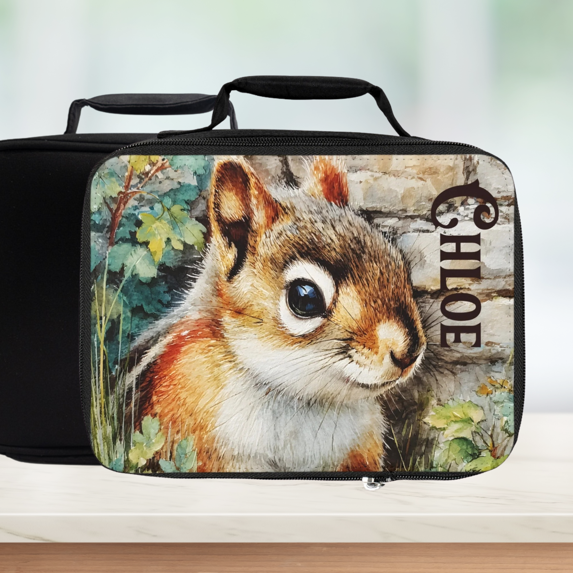  insulated lunch bag with a chipmunk design and 'Chloe' custom text on a counter with a blurred green background
