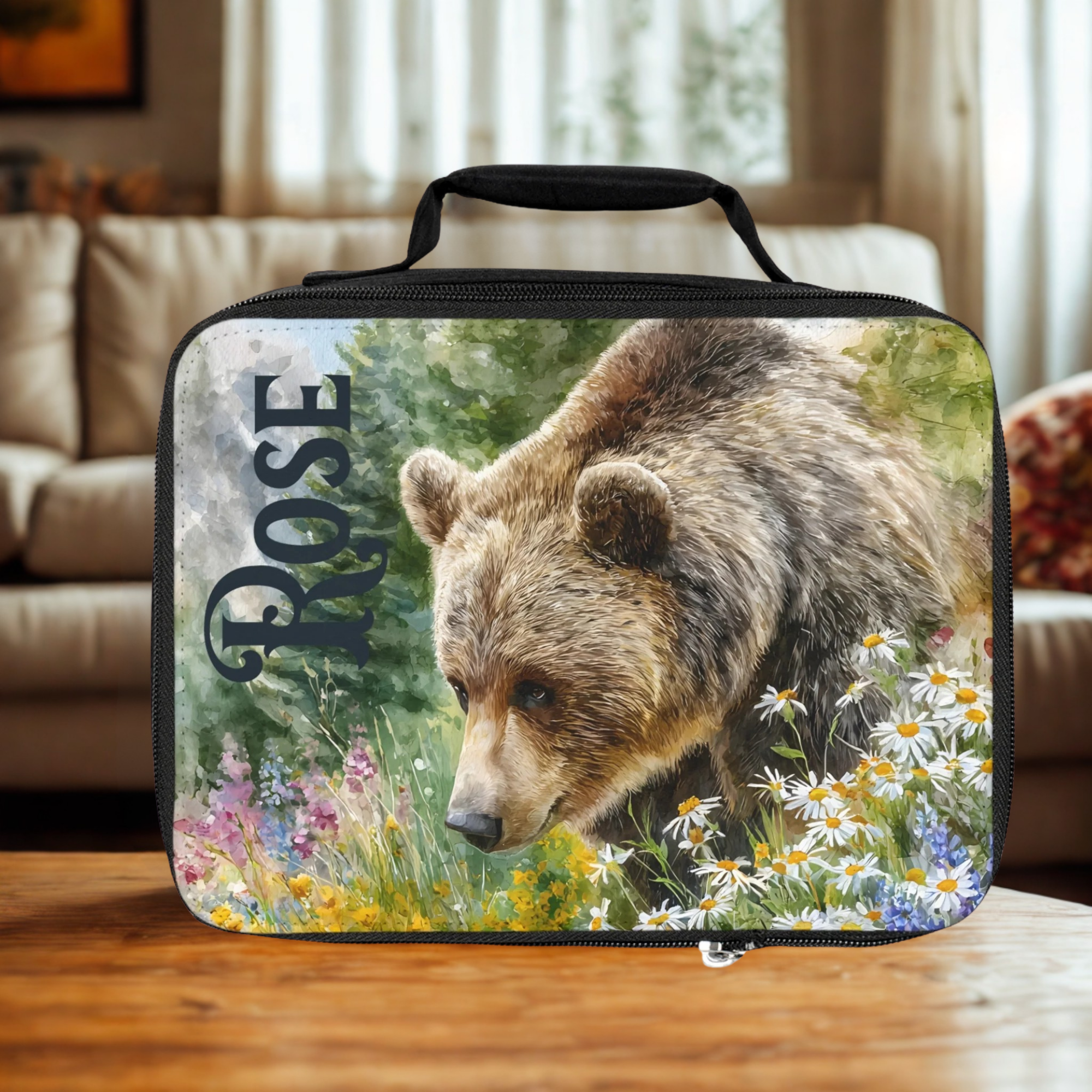  insulated lunch bag with bear design and 'Rose' custom text on a wooden living room table.