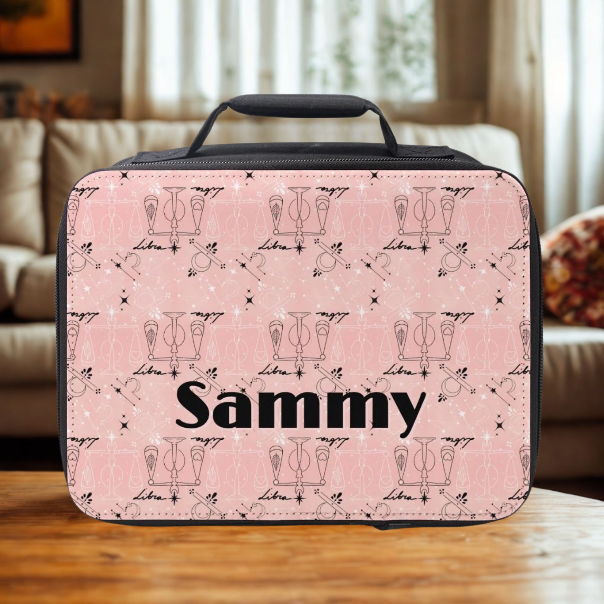 Pink Libra zodiac patterned lunch bag with 'Sammy' custom text on a wooden living room table.