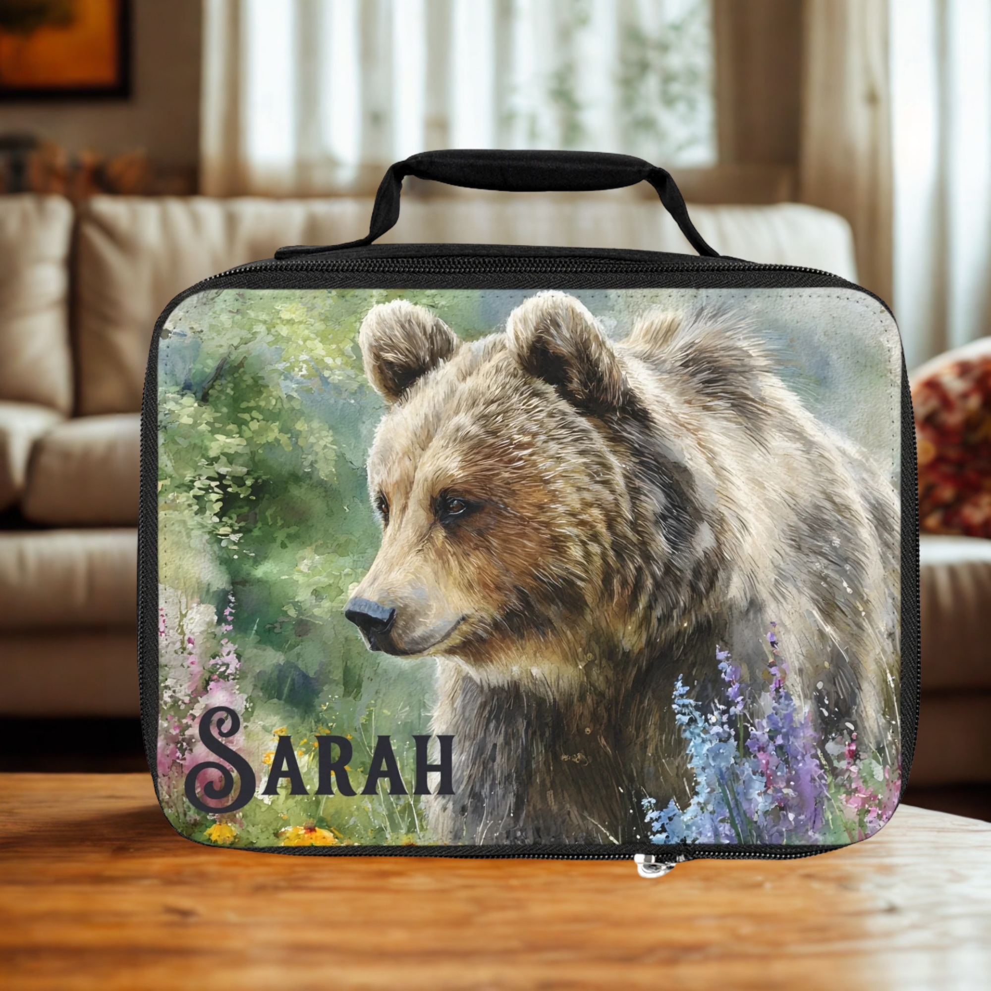  insulated lunch bag with bear design and 'Sarah' personalized text on a wooden living room table.