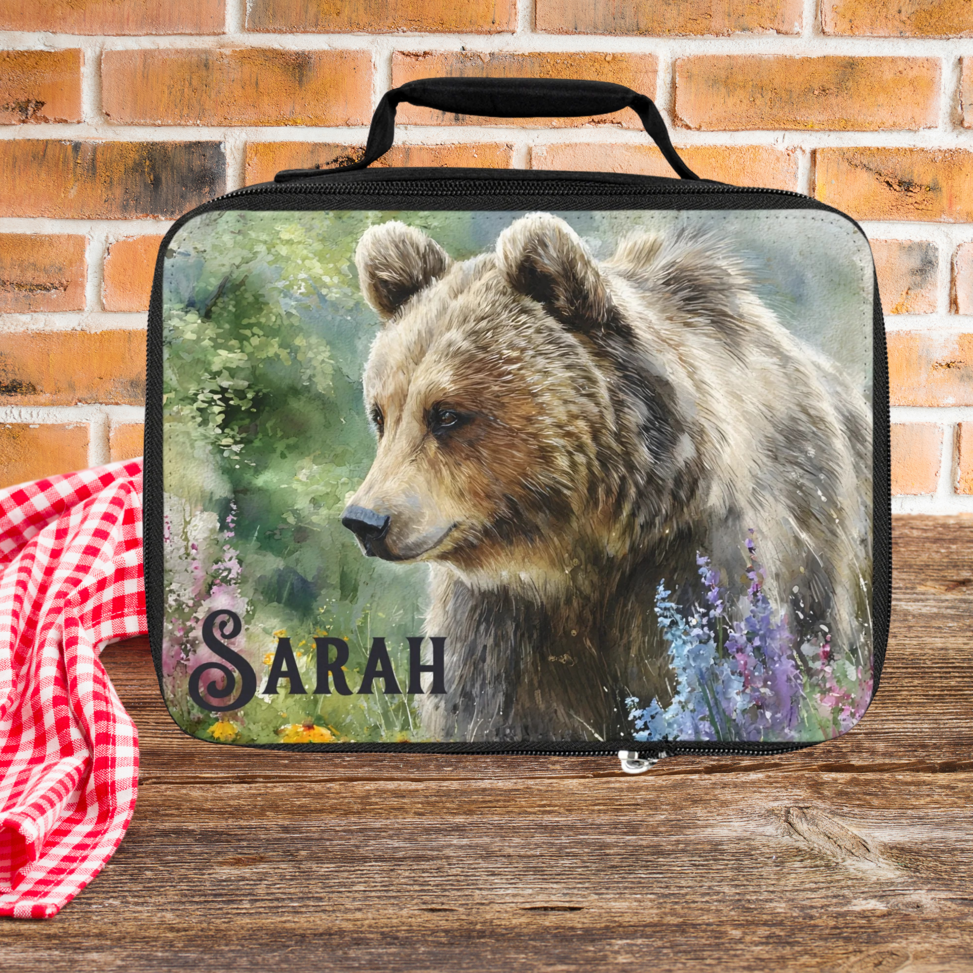  insulated lunch bag with bear design and 'Sarah' custom text on a wooden surface with brick background