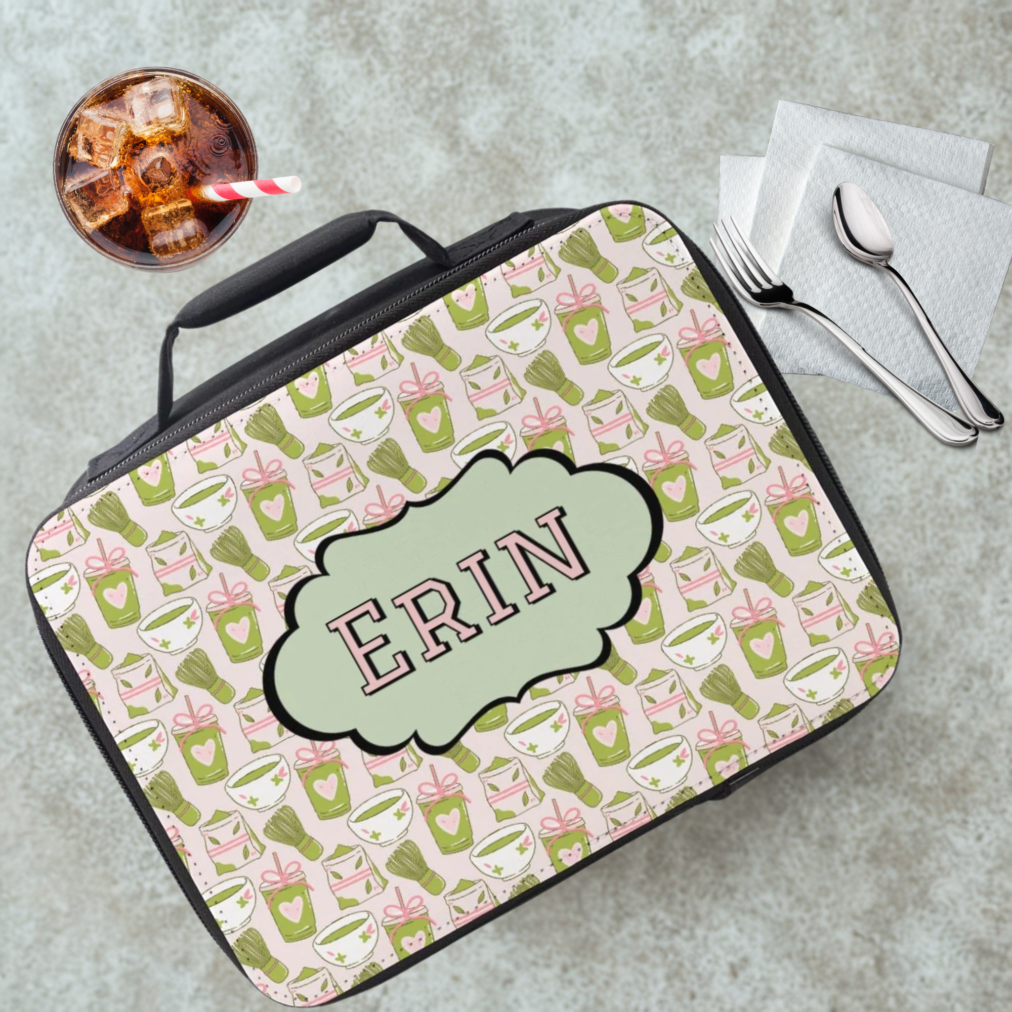Lunch bag with pattern and 'ERIN' monogram on a cafeteria table with a drink and utensils.