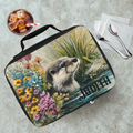 Lunch bag with an otter design and 'Judith' text on a table with a drink and utensils.