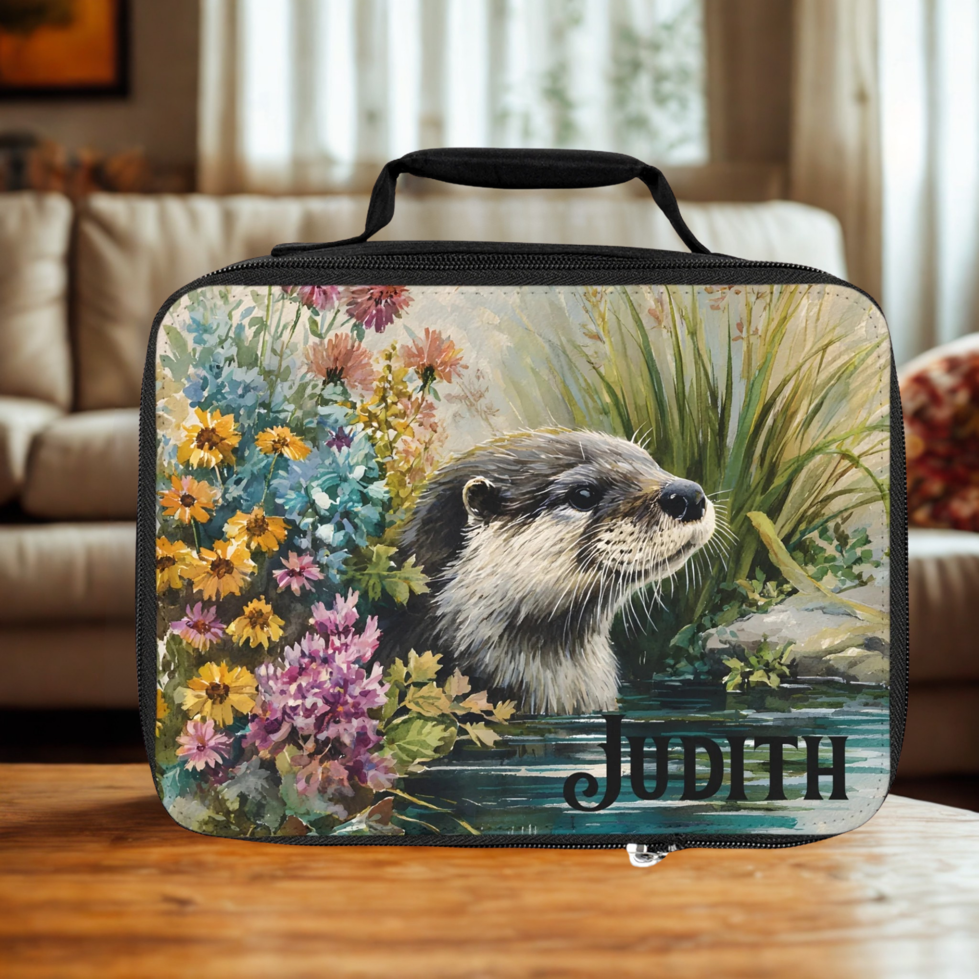 Personalized lunch bag with an otter design and the name 'Judith' on a wooden living room table.
