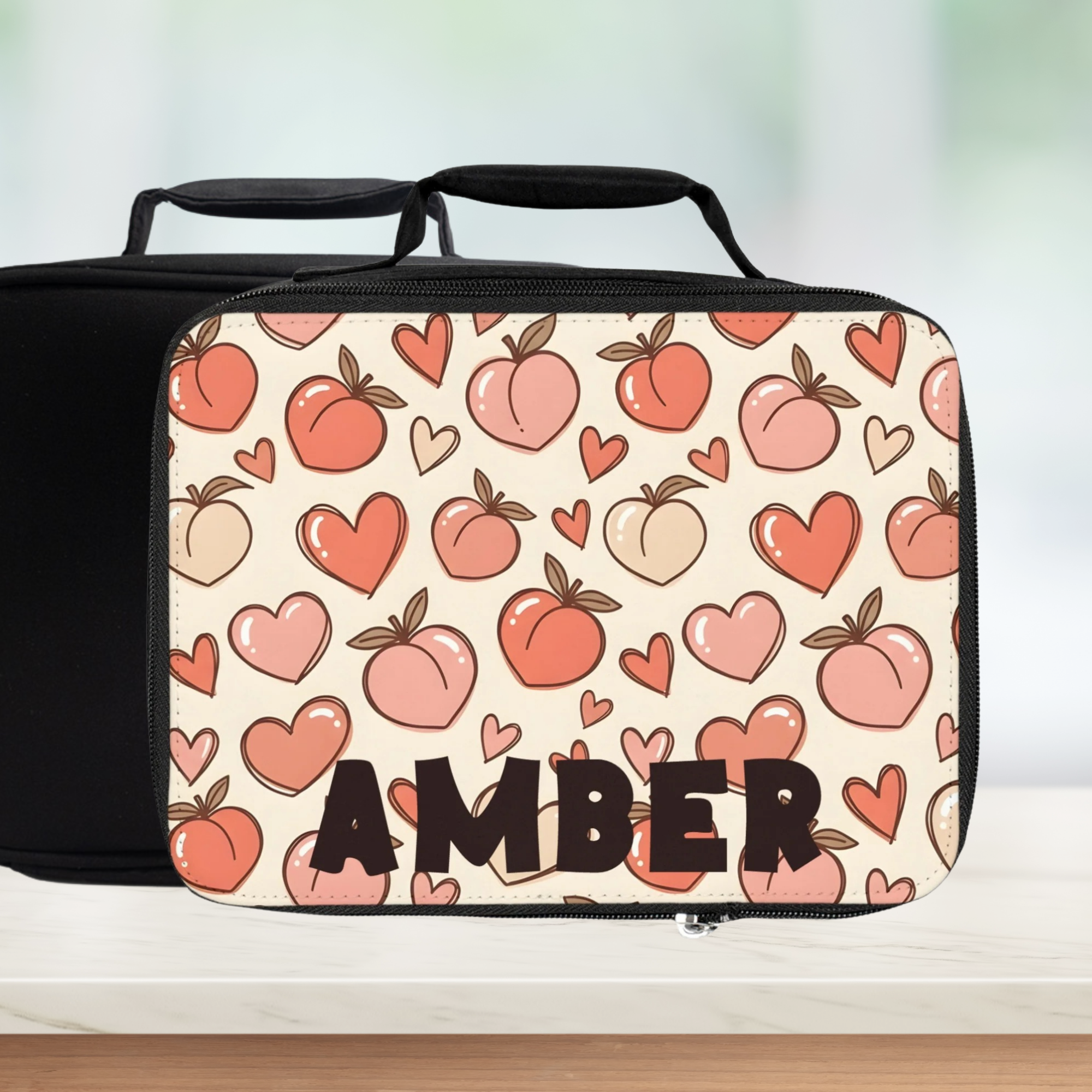  insulated lunch bag with peach and heart pattern and 'AMBER' personalized text on counter with blurred background