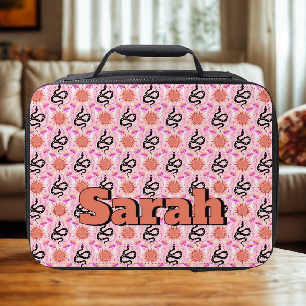 Pink lunch bag with snake pattern and 'Sarah' custom  text on a wooden table.