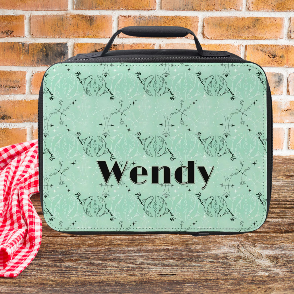 Green Pisces zodiac patterned lunch bag with 'Wendy' custom text on a wooden picnic table against a brick wall background