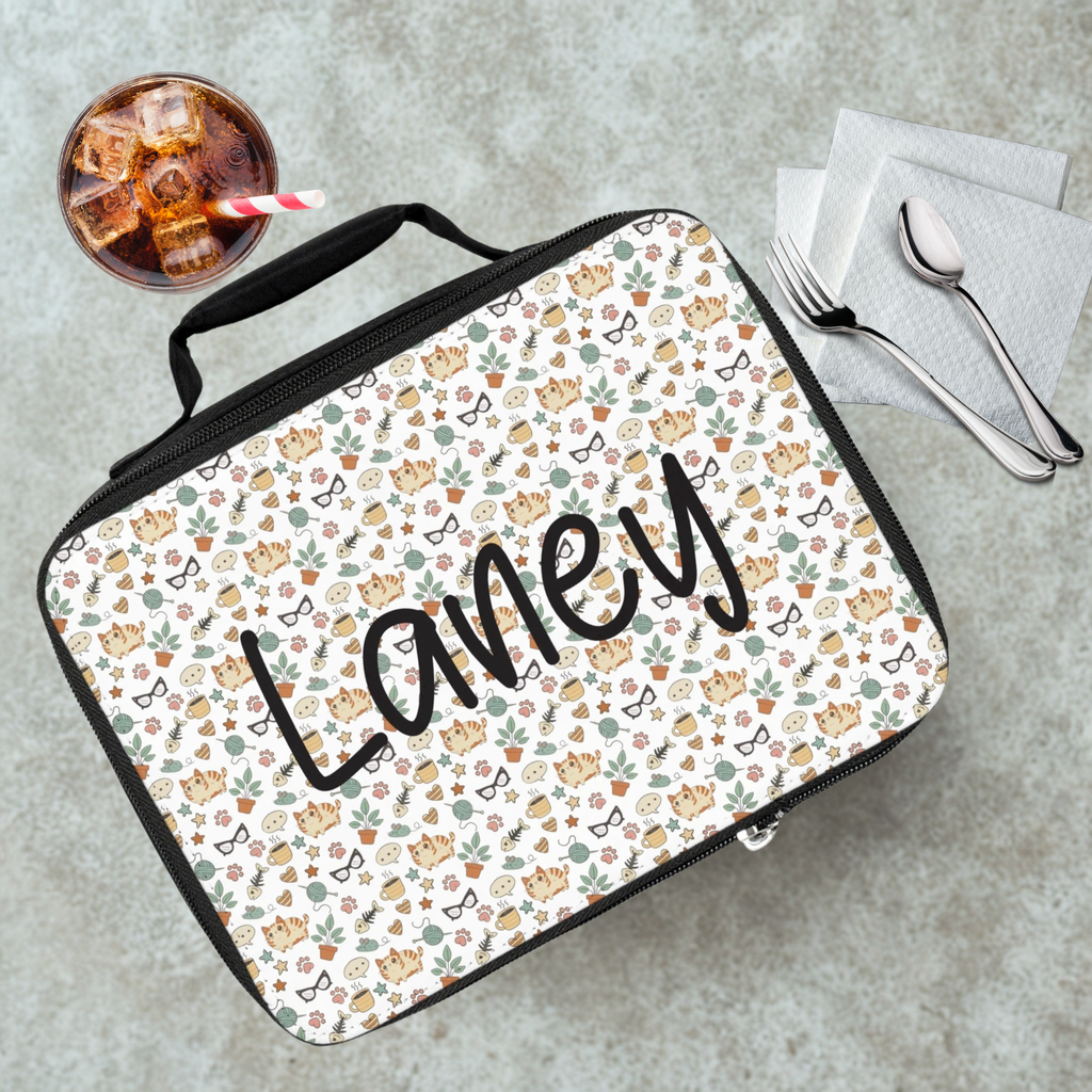 Lunch bag with cat  pattern and custom text on a cafeteria table with a drink and utensils.