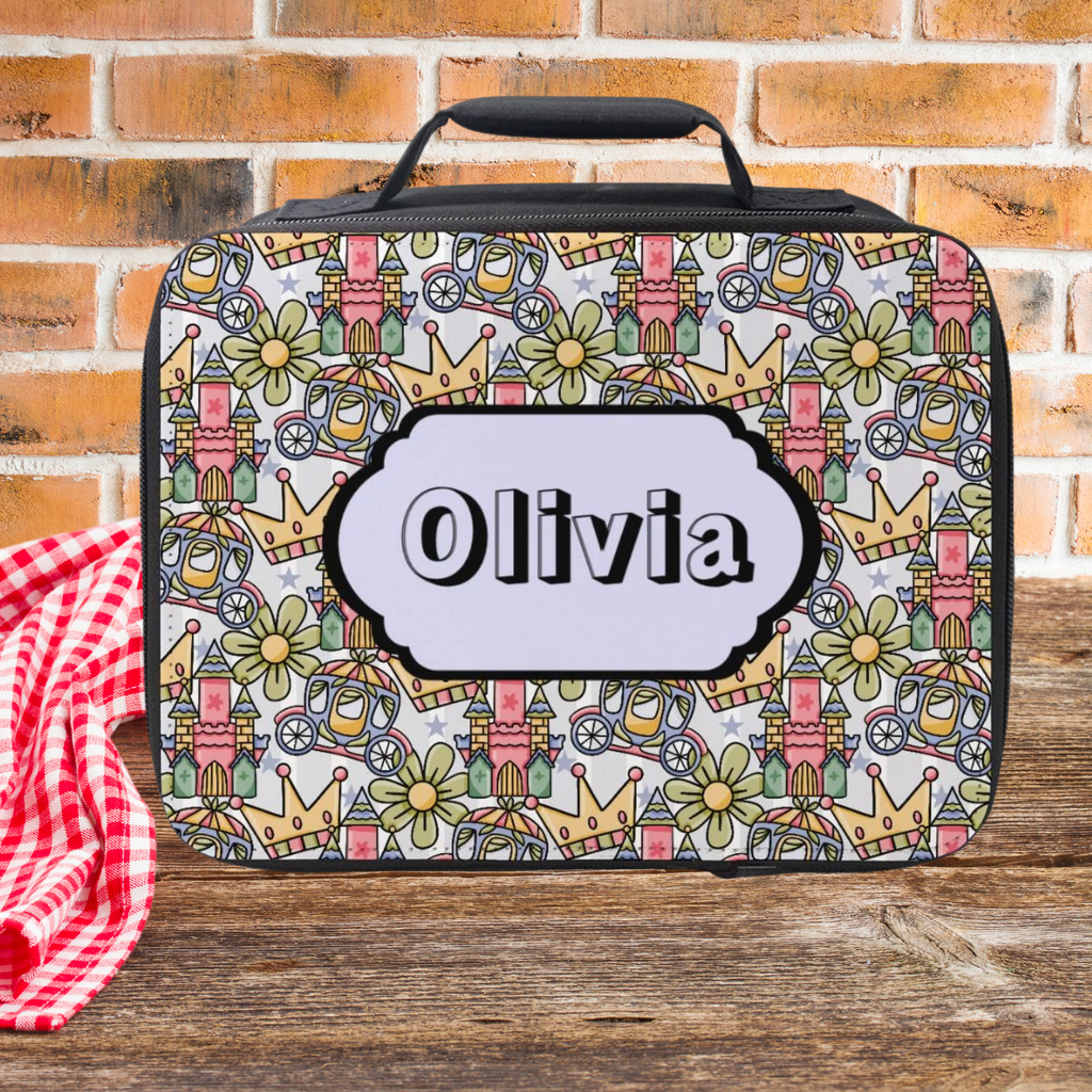 Colorful princess patterned lunch bag with 'Olivia' personalized name on a wooden picnic table and brick wall background
