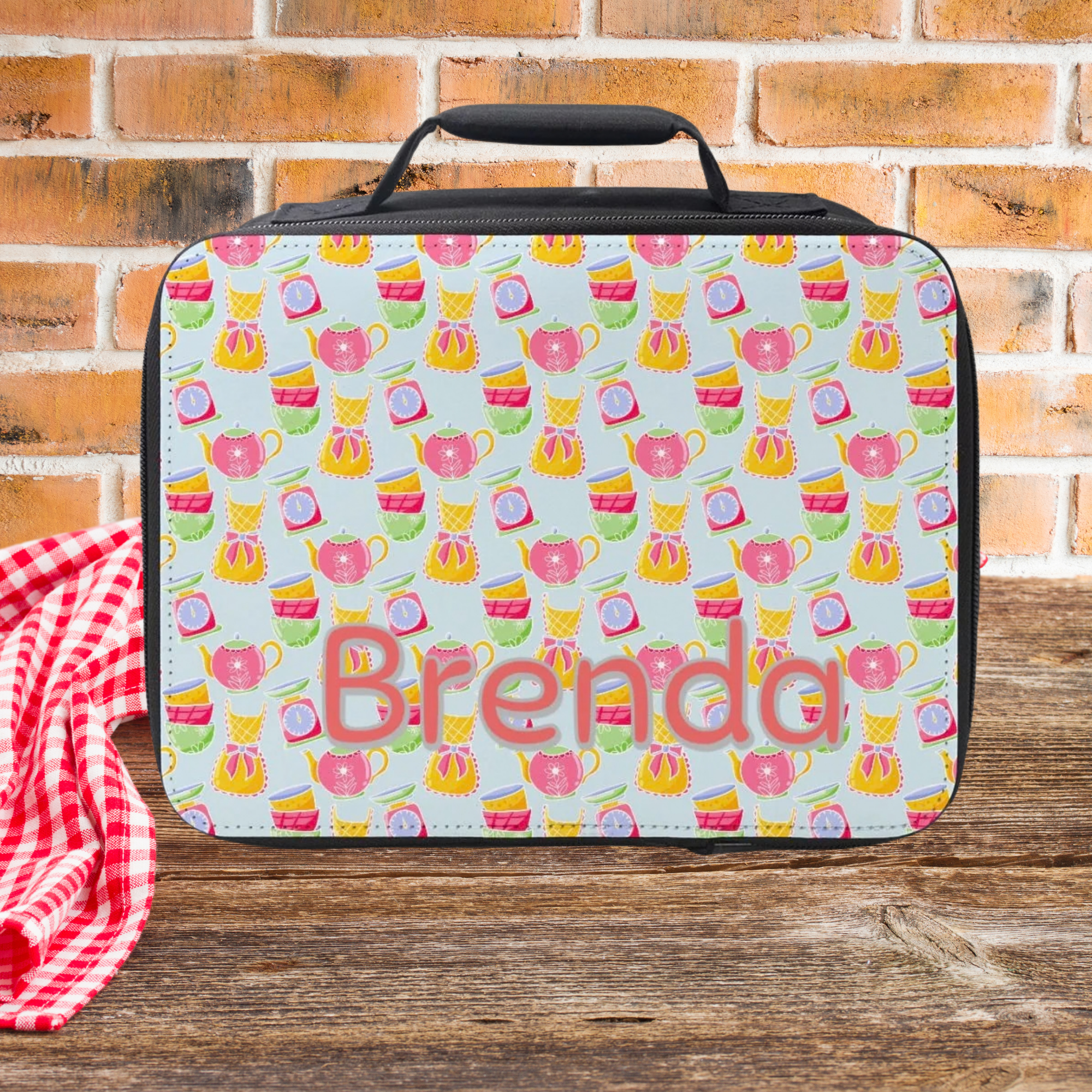 Colorful patterned lunch bag with 'Brenda' on it against a brick wall background