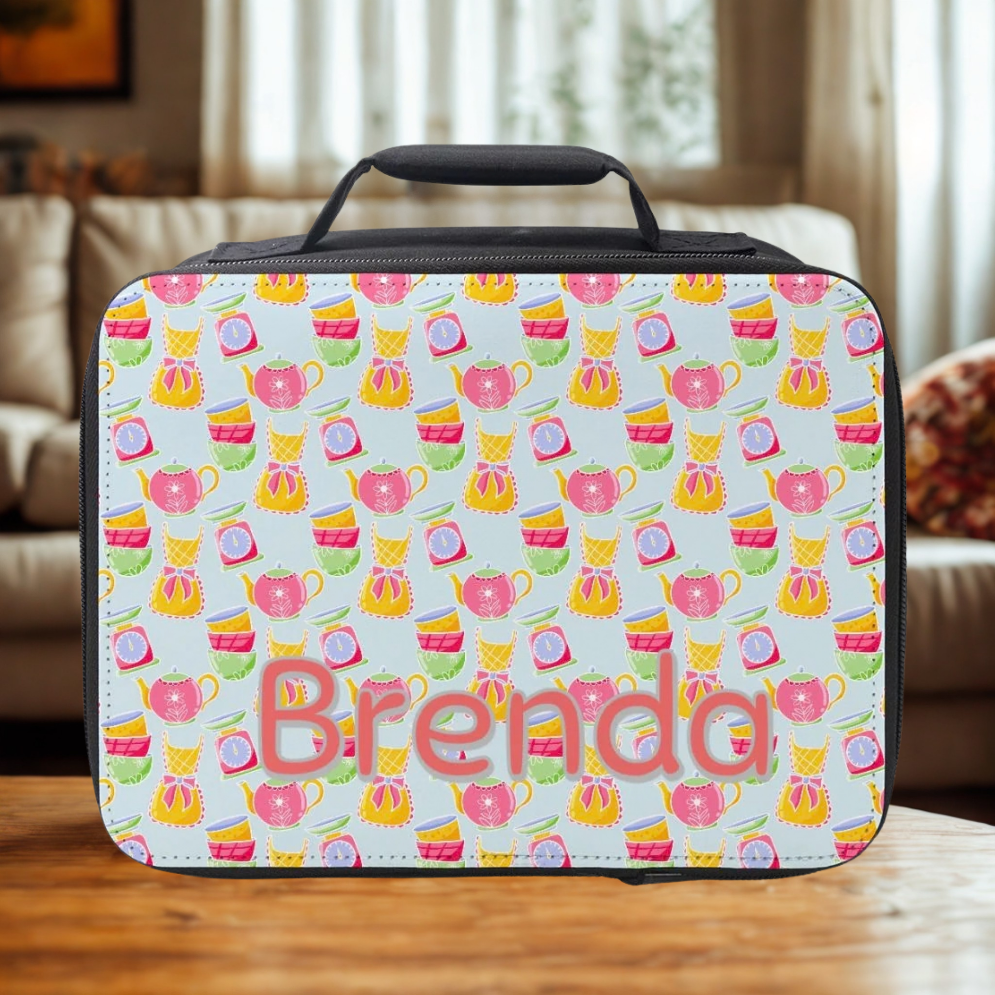  insulated lunch bag with tea cup pattern and 'Brenda' text on a wooden table in a cozy living room