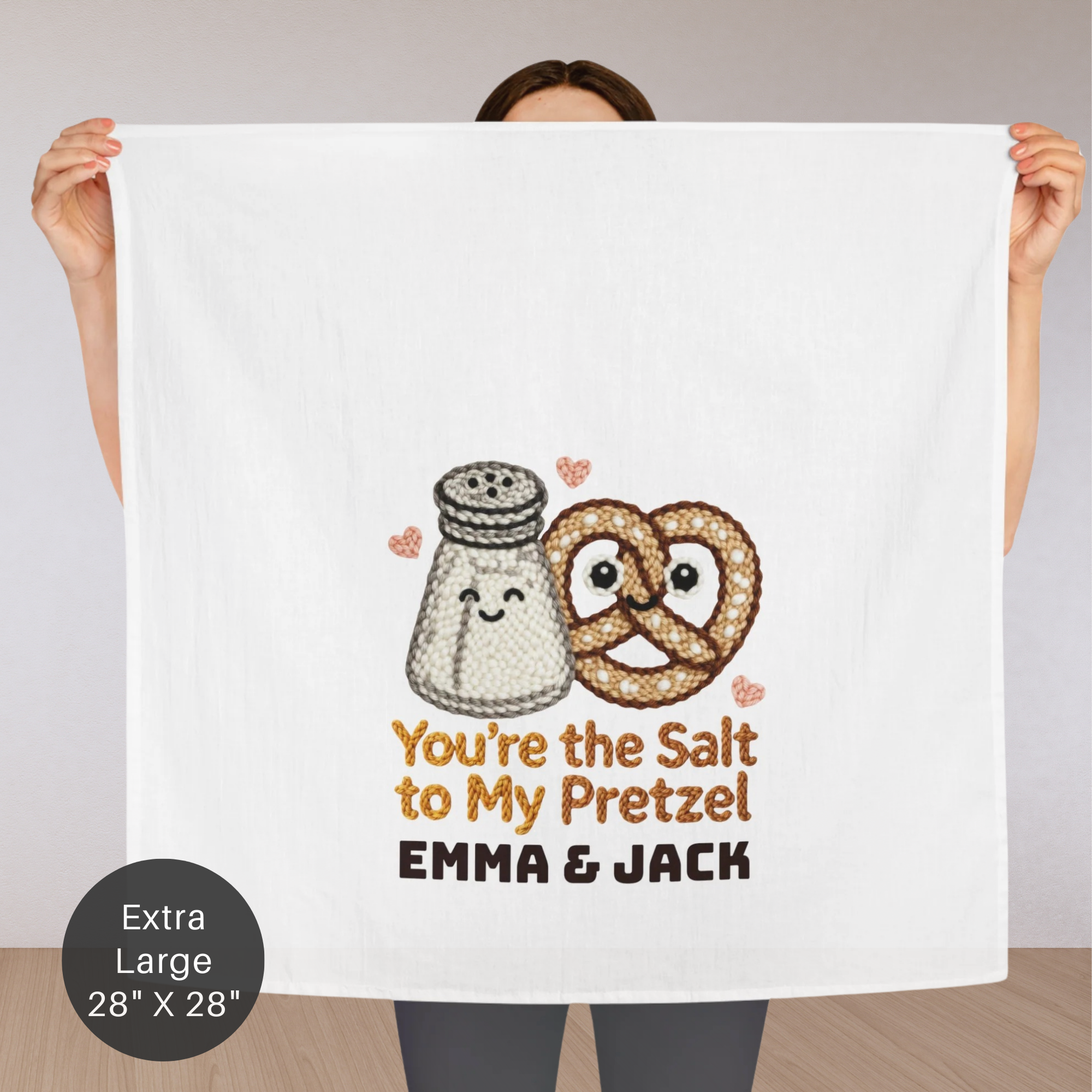 Person holding a towel with a salt and pretzel design and text 'You're the Salt to my Pretzel Emma & Jack'.
