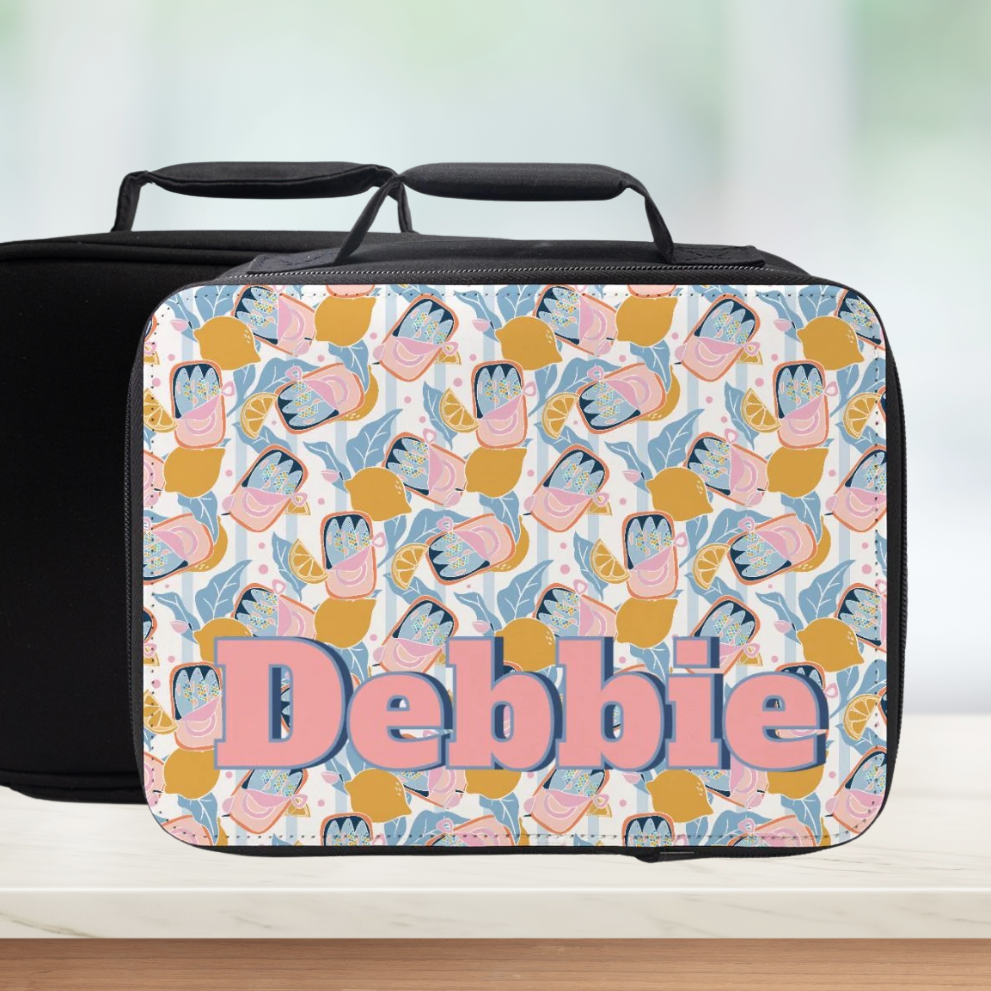 Personalized lunch bag with floral pattern and name 'Debbie' on a blurred background