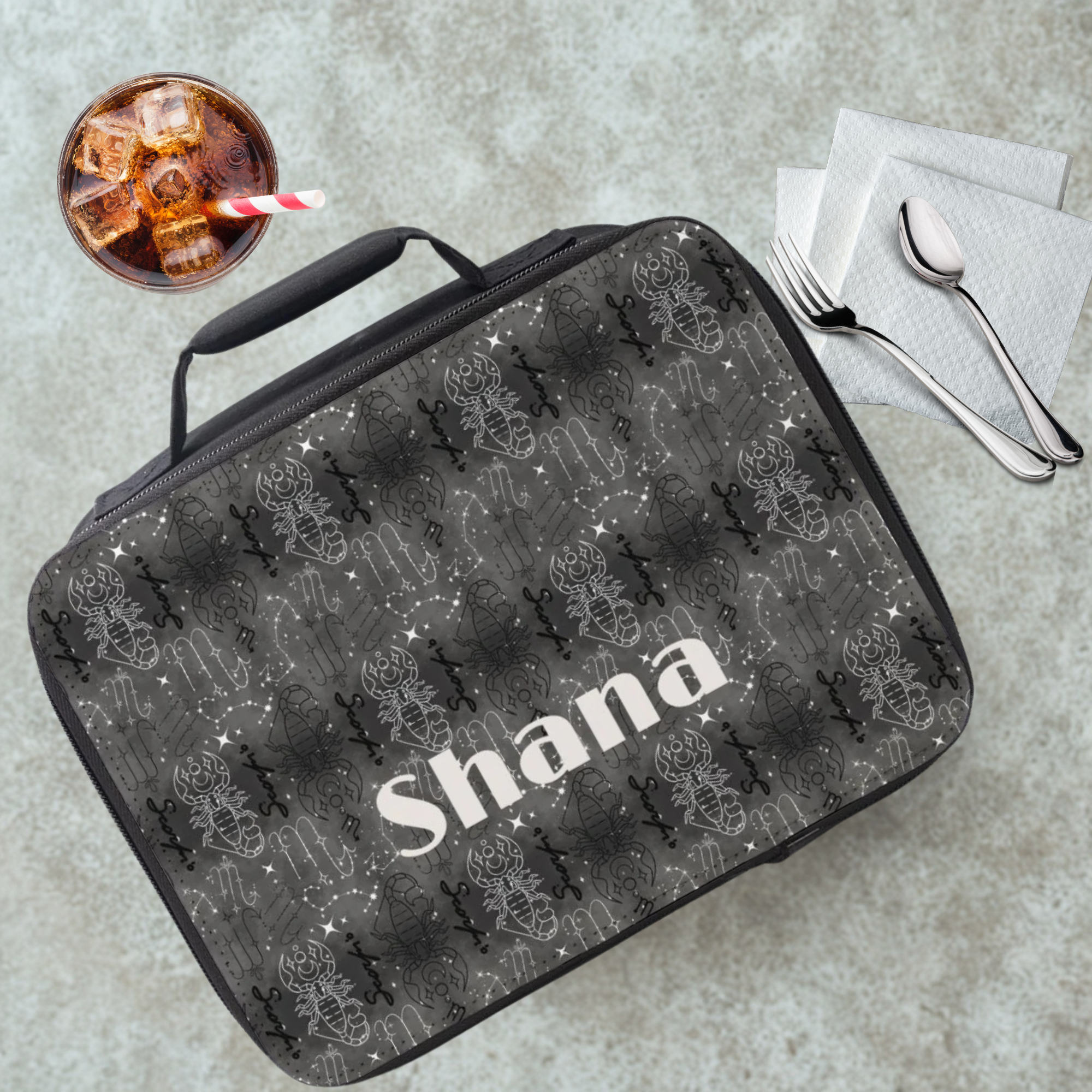 Scorpio insulated lunch bag with 'Shana' personalized name on a cafeteria table with a drink and utensils.