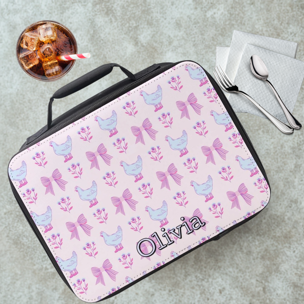 Personalized lunch bag with chicken and bow pattern on a gray table with a drink and utensils.