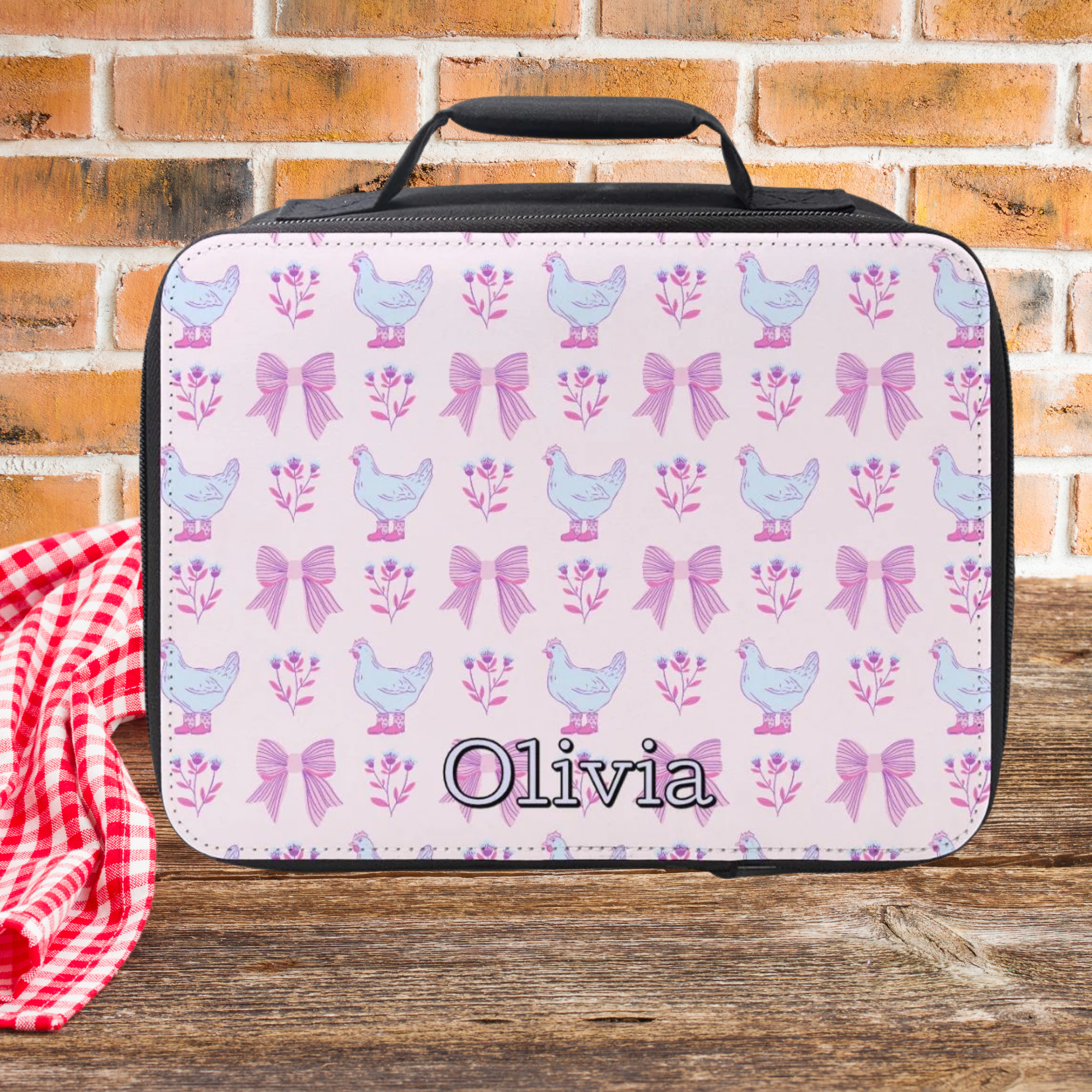  insulated lunch bag with chicken and bow pattern on a wooden picnic table with brick background