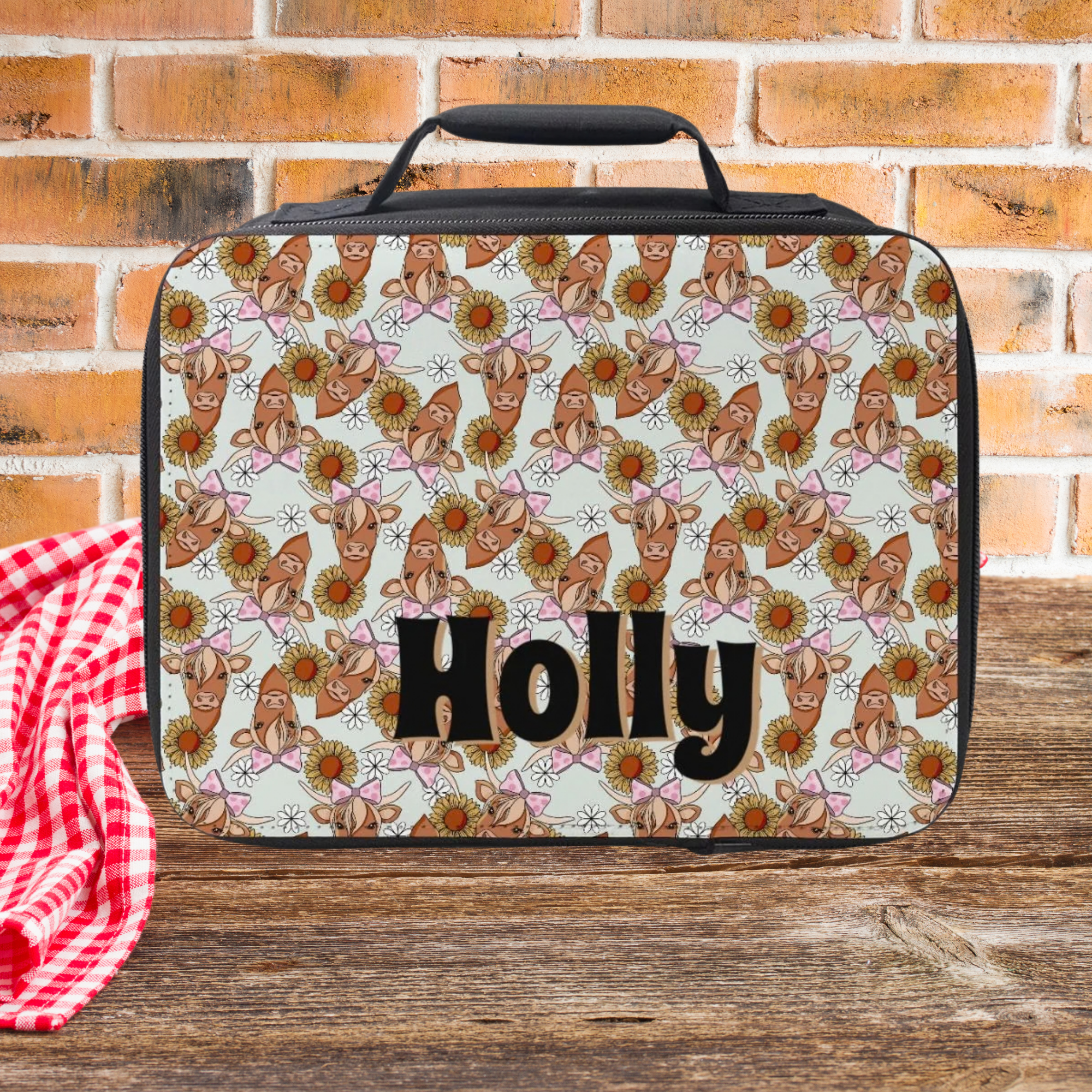 Lunch bag with floral pattern and 'Holly' text on a wooden picnic table with brick background